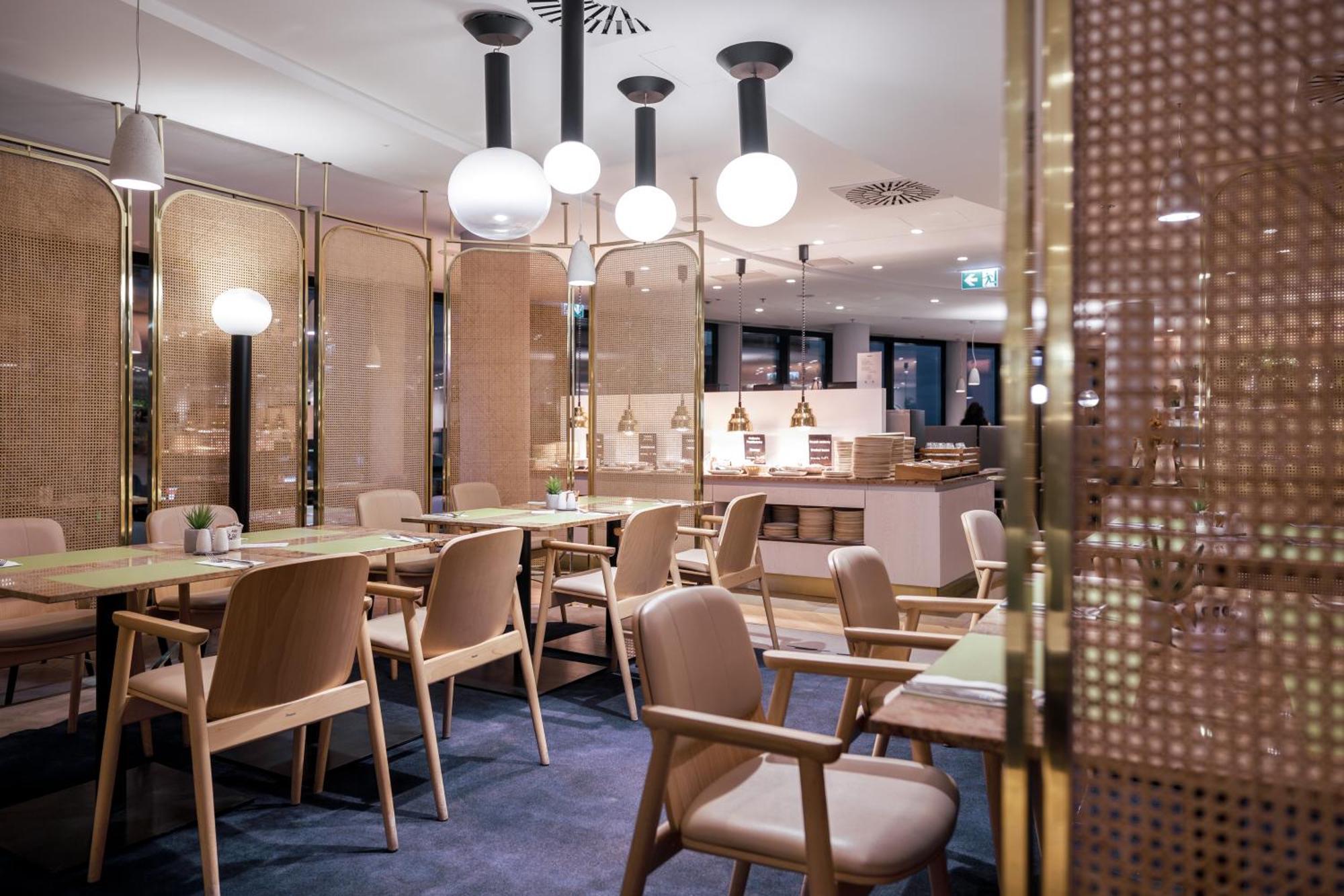 Radisson Blu Resort シフィノウイシチェ エクステリア 写真 The photo shows a modern restaurant interior. There are wooden tables and chairs arranged neatly. The atmosphere appears warm and inviting, with soft lighting provided by round pendant lamps hanging from the ceiling. Partitions made of woven material