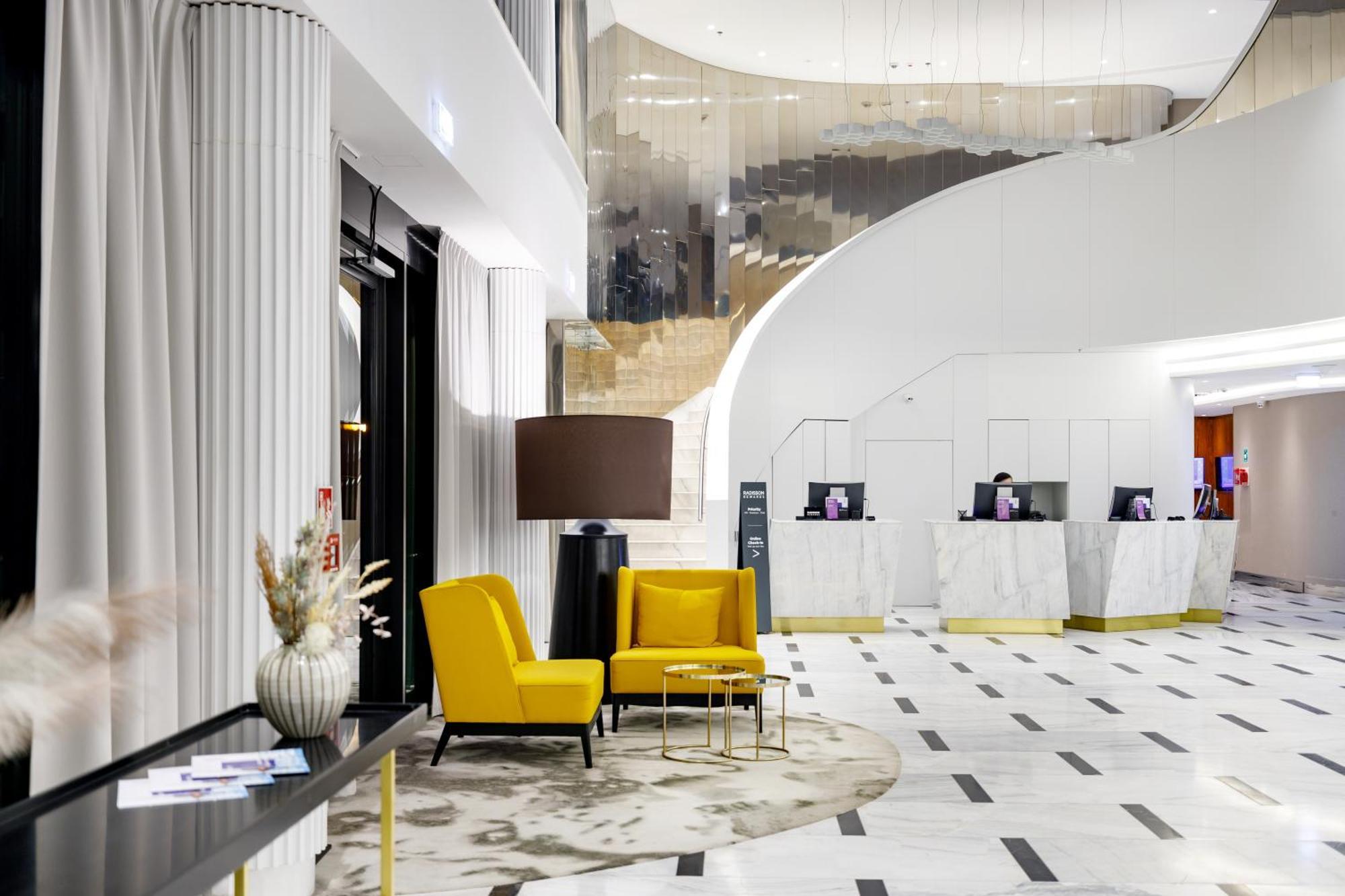 Radisson Blu Resort シフィノウイシチェ エクステリア 写真 The photo shows the interior of a modern hotel lobby. The space features a stylish design with a combination of yellow and neutral-colored seating, including two yellow armchairs and a small table. In the background, there is a reception area with ma