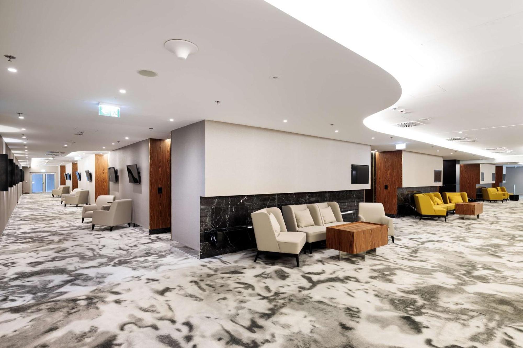 Radisson Blu Resort シフィノウイシチェ エクステリア 写真 The photo shows a modern interior space, likely a lobby or lounge area. The flooring features a patterned carpet, and the walls are neutral in color, creating a calm ambiance. There are comfortable seating arrangements, including a group of beige cha
