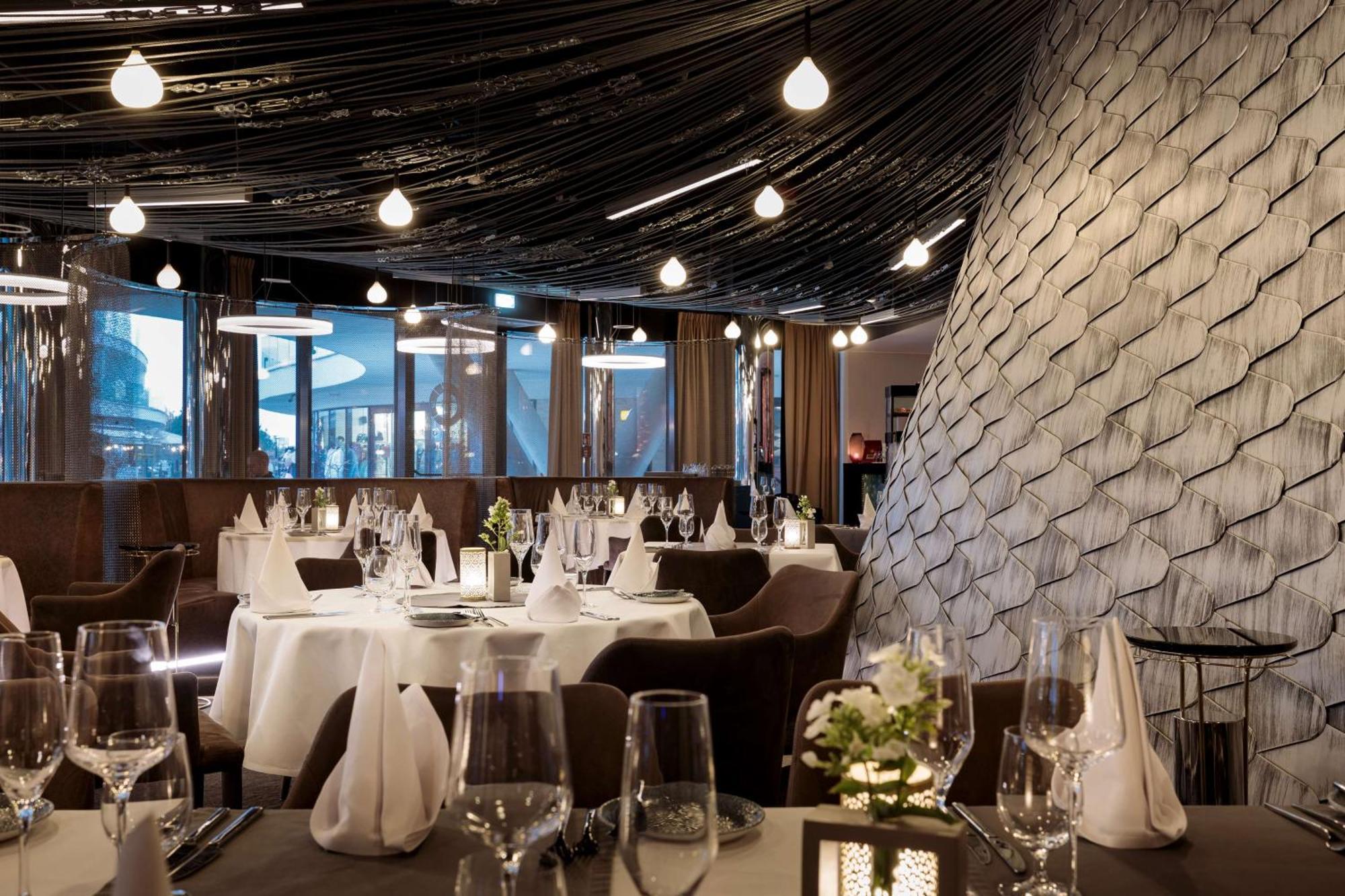 Radisson Blu Resort シフィノウイシチェ エクステリア 写真 The photo shows a stylish restaurant interior. The dining area features elegantly set tables with white tablecloths, glassware, and folded napkins. There are decorative elements like small floral arrangements on the tables. The ceiling is adorned wit