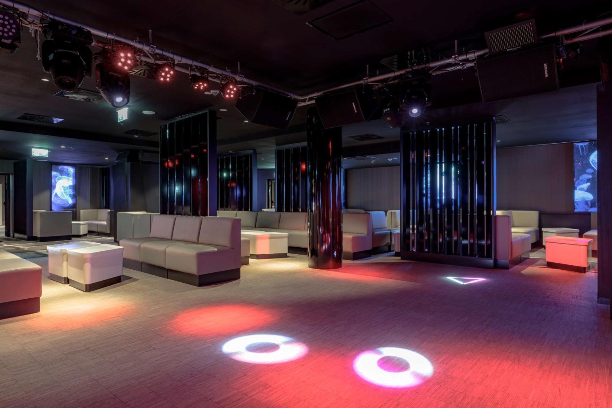 Radisson Blu Resort シフィノウイシチェ エクステリア 写真 The photo depicts a modern nightclub interior, featuring a spacious layout with sleek, minimalist seating arrangements. The room has plush seating along the walls, and the floor is illuminated with circular lights in varying colors, creating a vibran