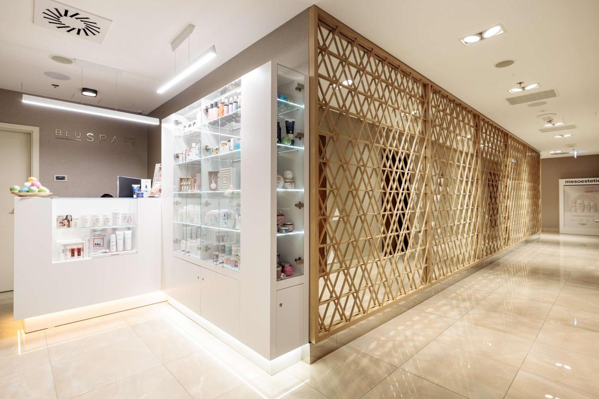 Radisson Blu Resort シフィノウイシチェ エクステリア 写真 The photo shows a modern interior, likely from a spa or skincare clinic. On the left, there is a reception area with a sleek white counter and an illuminated display showcasing various skincare products. The wall behind the reception features a glass